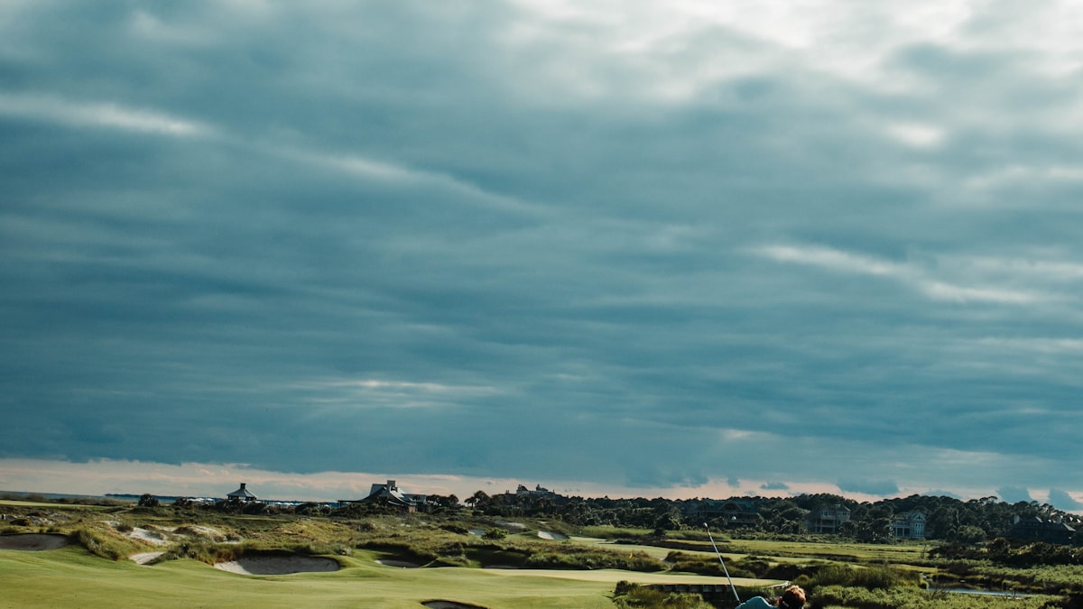 Empty golf course fairway under moody clouds at dusk